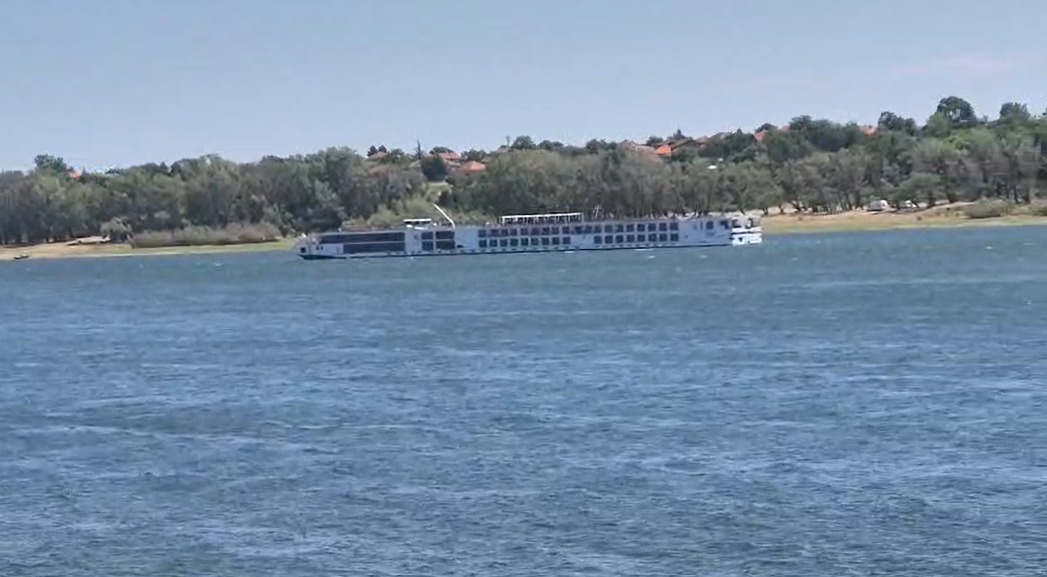 Navă de croazieră pe fluviu lângă mal împădurit