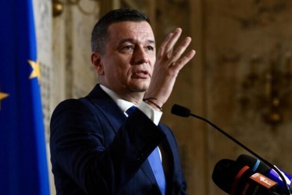 Bărbat în costum ținând discurs la pupitru